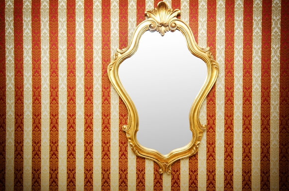 A shiny golden mirror on a striped wall highlights a fresh decor piece in San Jose, CA.