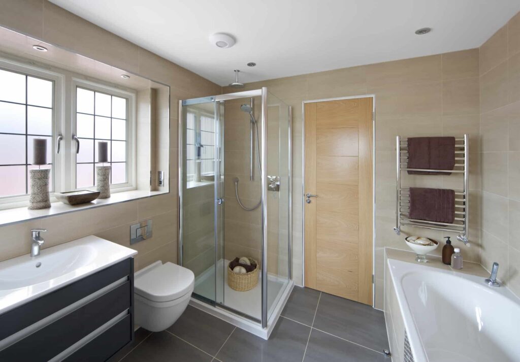 Modern bathroom scene with a shower, sink, & toilet, featuring glass shower doors in San Jose.