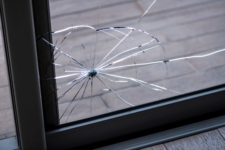 Close-up of a shattered double-pane window with visible cracks and damage in San Jose