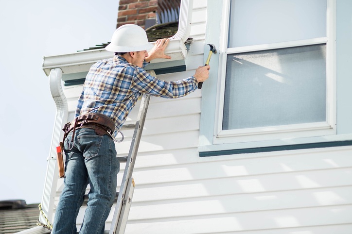 Worker on ladder board up windows for hurricanes in San Jose, CA