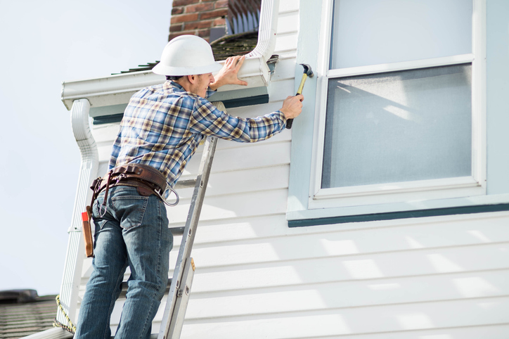 Worker on ladder board up windows for hurricanes in San Jose, CA